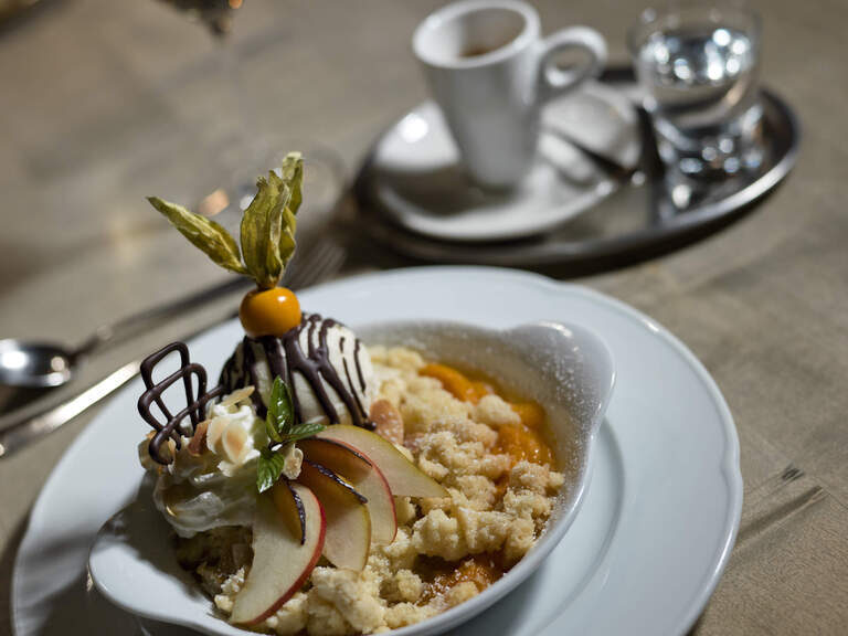 Ein stilvoll angerichtetes Dessert auf einem weißen Teller mit kunstvoller Buttercreme- und Fruchtgarnitur.